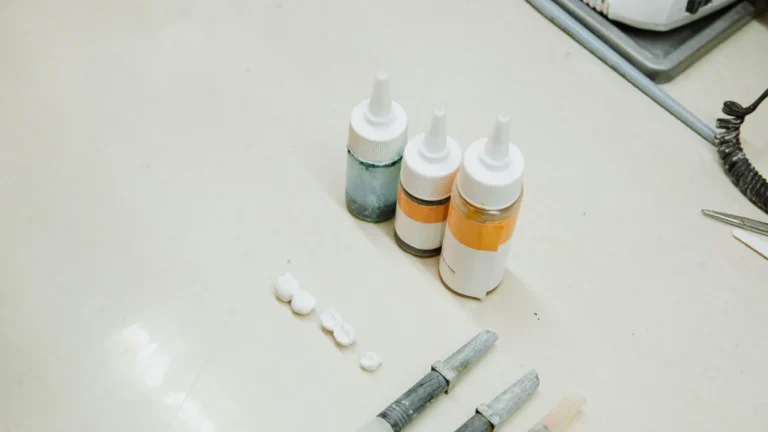 From above of various medical bottle and tubes for making denture and fake teeth placed on white table in dental clinic