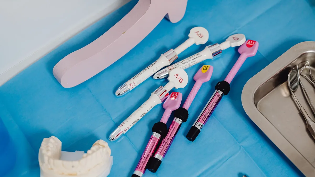 A detailed view of dental instruments and materials arranged on a sterile blue surface in a clinical setting.