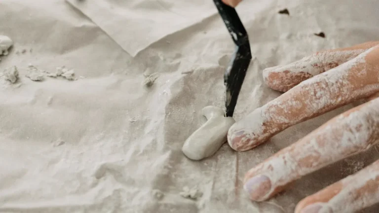 Hands working with clay on a textured surface, showcasing creativity and craftsmanship.